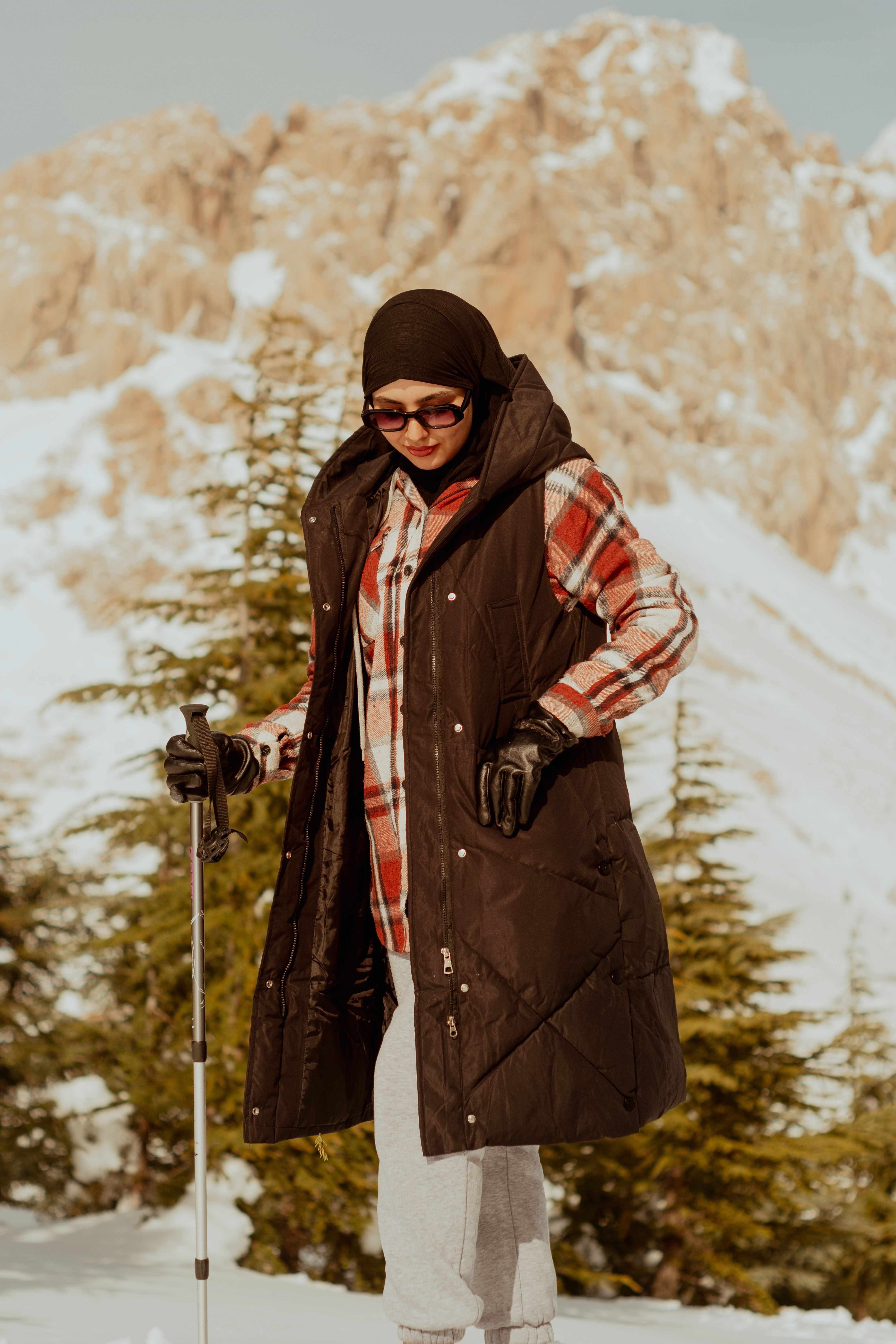 Stylish winter fashion portrait of a woman in a snowy mountainous setting.