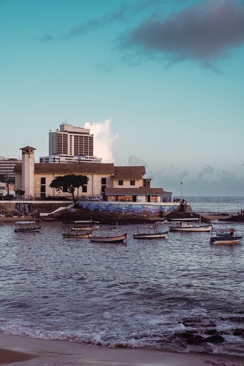 Free Scenic view of boats anchored at a tranquil seaside with modern and historic buildings along the waterfront. Stock Photo
