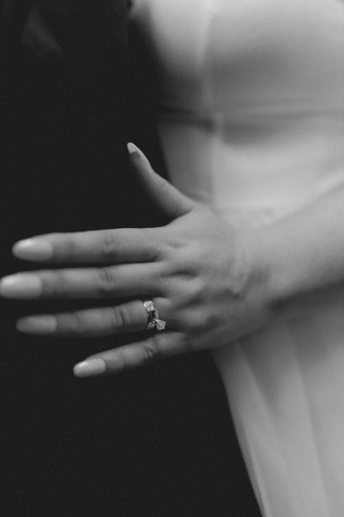 A black and white photo of a woman's hand holding a wedding ring