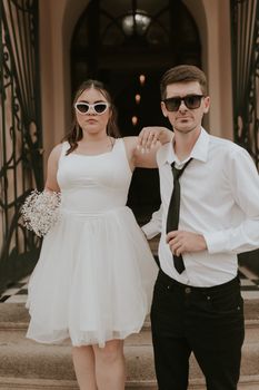 Fashionable couple poses in chic wedding attire, embodying modern elegance.