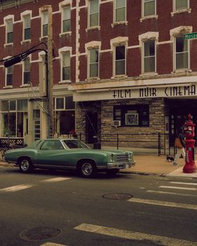 Classic Chevrolet Monte Carlo parked by a cinema, evoking urban nostalgia.