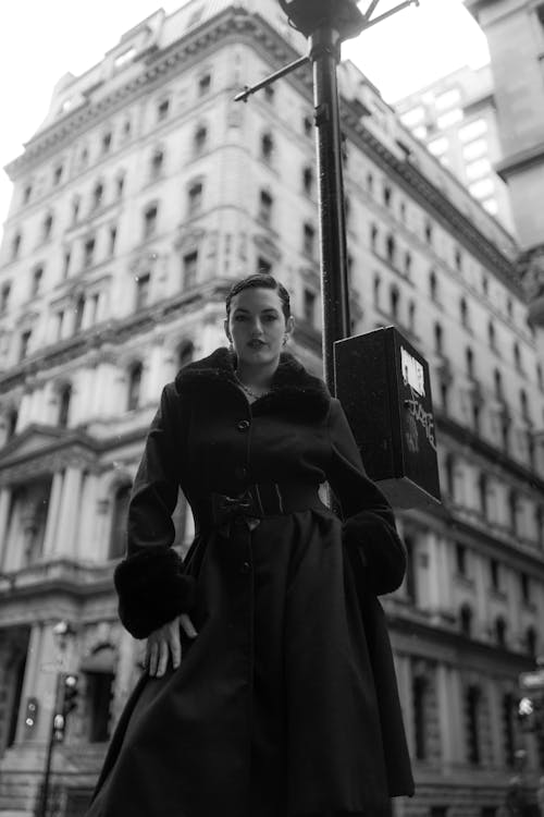 A woman in a black coat and hat standing on a street corner