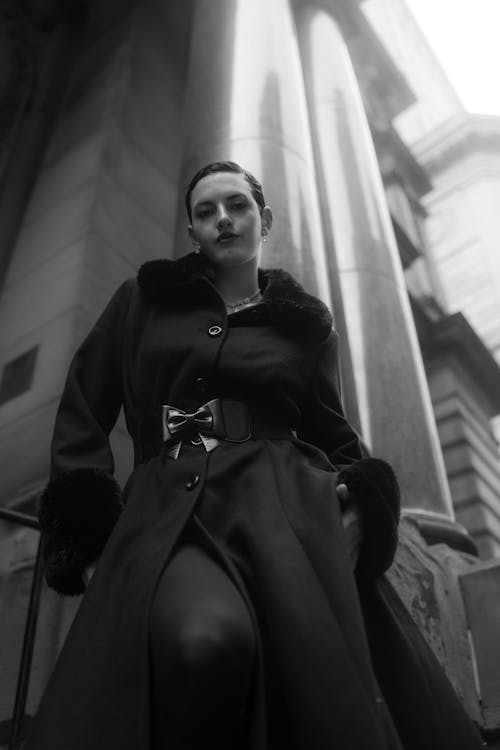 A woman in a black coat and tights posing for a photo