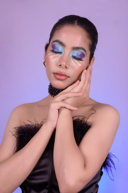 A woman with blue and black makeup and feathers
