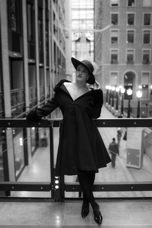 A woman in a black coat and hat standing on a balcony