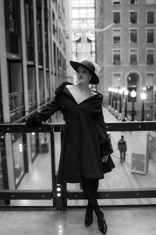 A woman in a hat and coat standing on a balcony