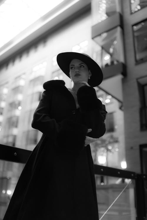 A woman in a black coat and hat standing on a balcony