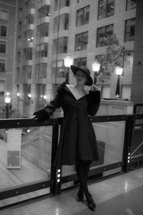 A woman in a black coat and hat standing on a balcony