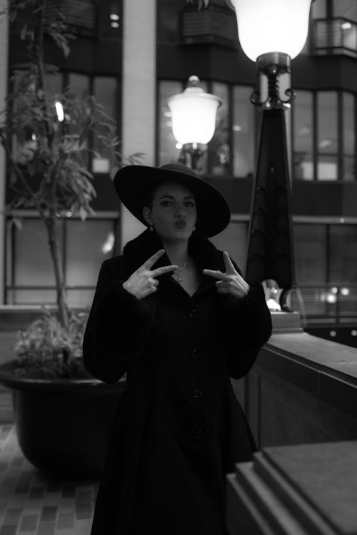 A woman in a black hat and coat is posing for a photo