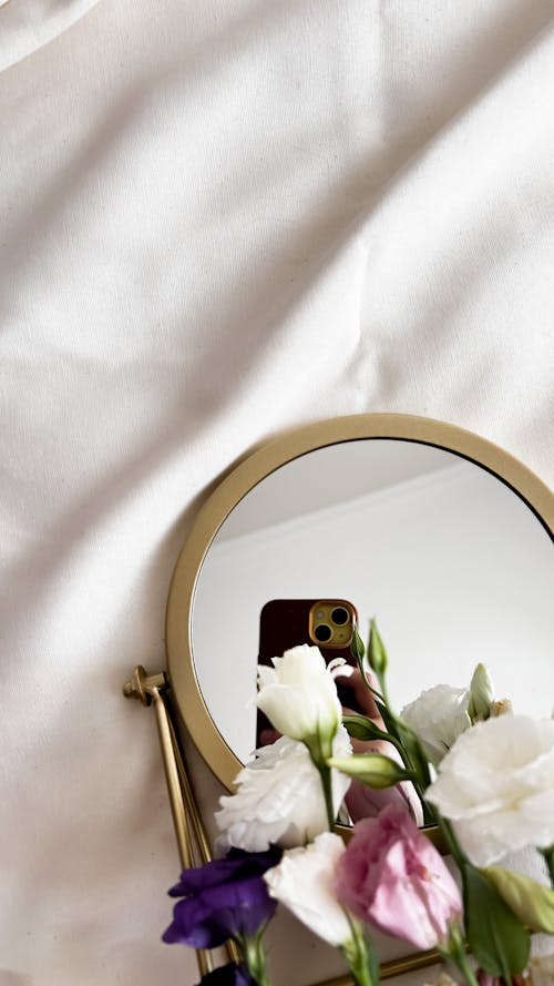 A mirror with flowers on it and a vase