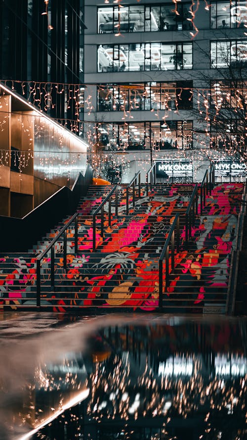 A stairway with lights and a reflection of the city