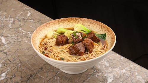 A bowl of noodles with meat and vegetables