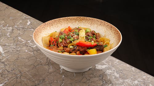 A bowl of food with vegetables and meat on top