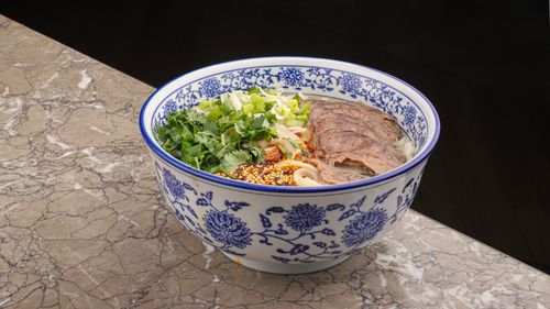 Free Close-up of a flavorful beef noodle soup with vegetables, served in a decorative bowl. Stock Photo
