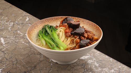 A bowl of noodles with meat and vegetables