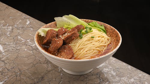 A bowl of noodles with meat and vegetables