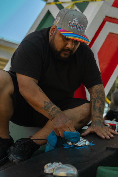 A man in a hat and a tattoo is cutting up a piece of paper