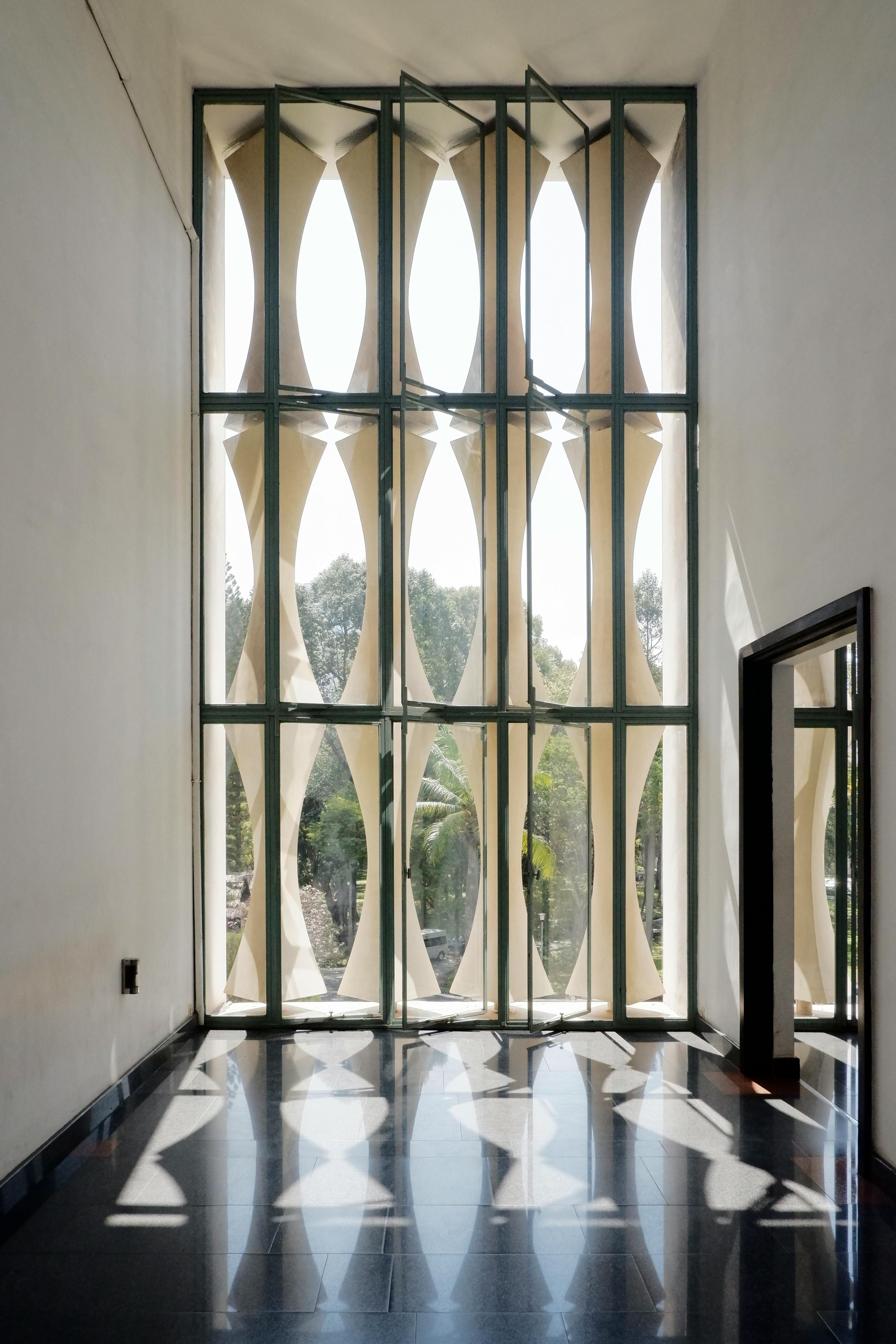 Sunlit geometrical windows casting reflections on black flooring in a modern interior space.
