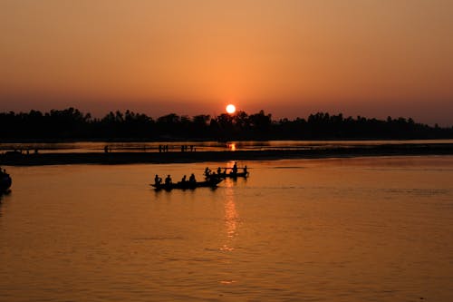 A group of people in boats on a river at sunset
