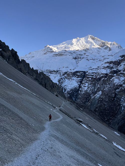 Free A person hiking along a narrow path in a snowy mountain landscape, under a clear sky. Stock Photo