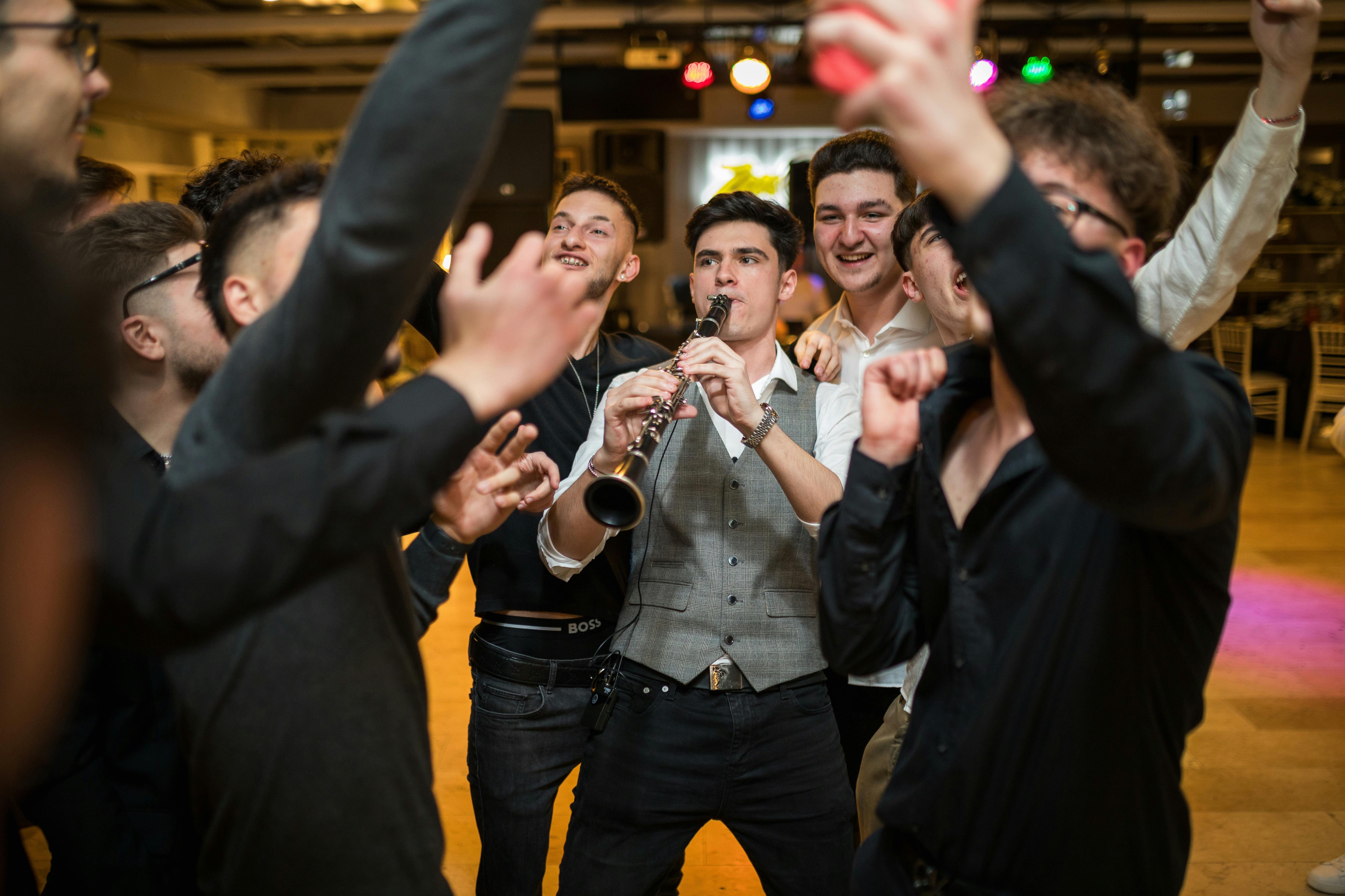 Group of teenagers having fun playing a clarinet at a lively indoor party.