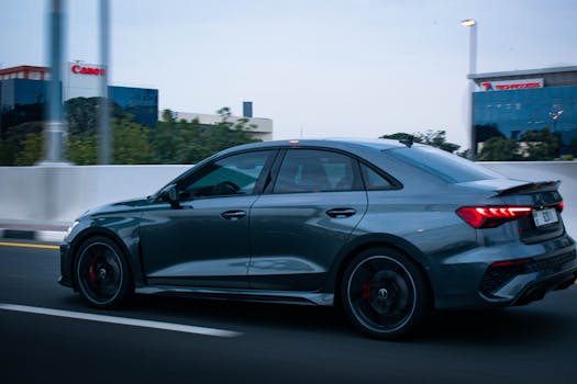 Dynamic shot of a sleek Audi car speeding along a city street, showcasing modern automotive design and urban lifestyle.