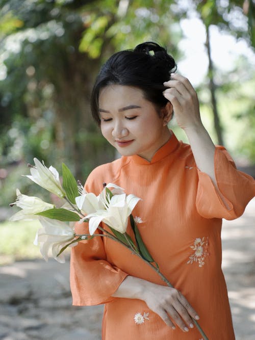 A woman in an orange dress holding flowers