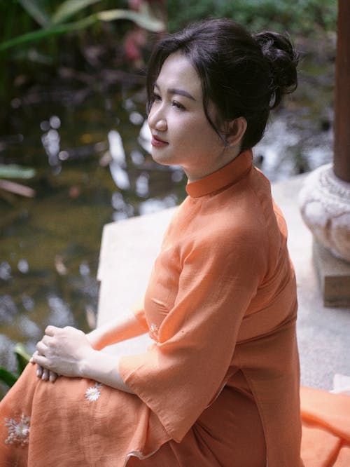 A woman in an orange dress sitting on a bench