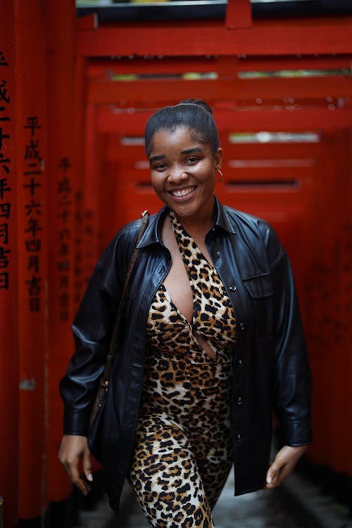 A woman in a leopard print outfit standing in front of a red gate