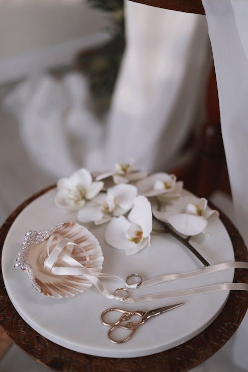 A white plate with a pair of scissors and a flower