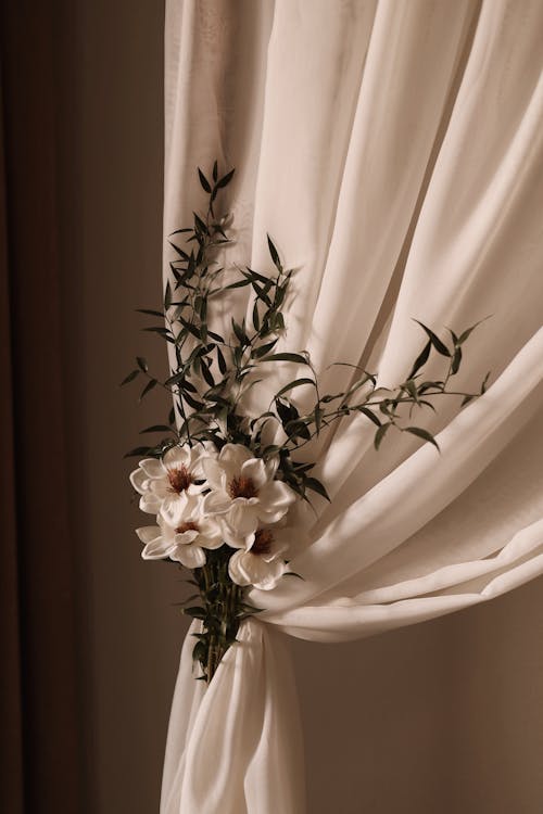 A white flower is placed on a curtain