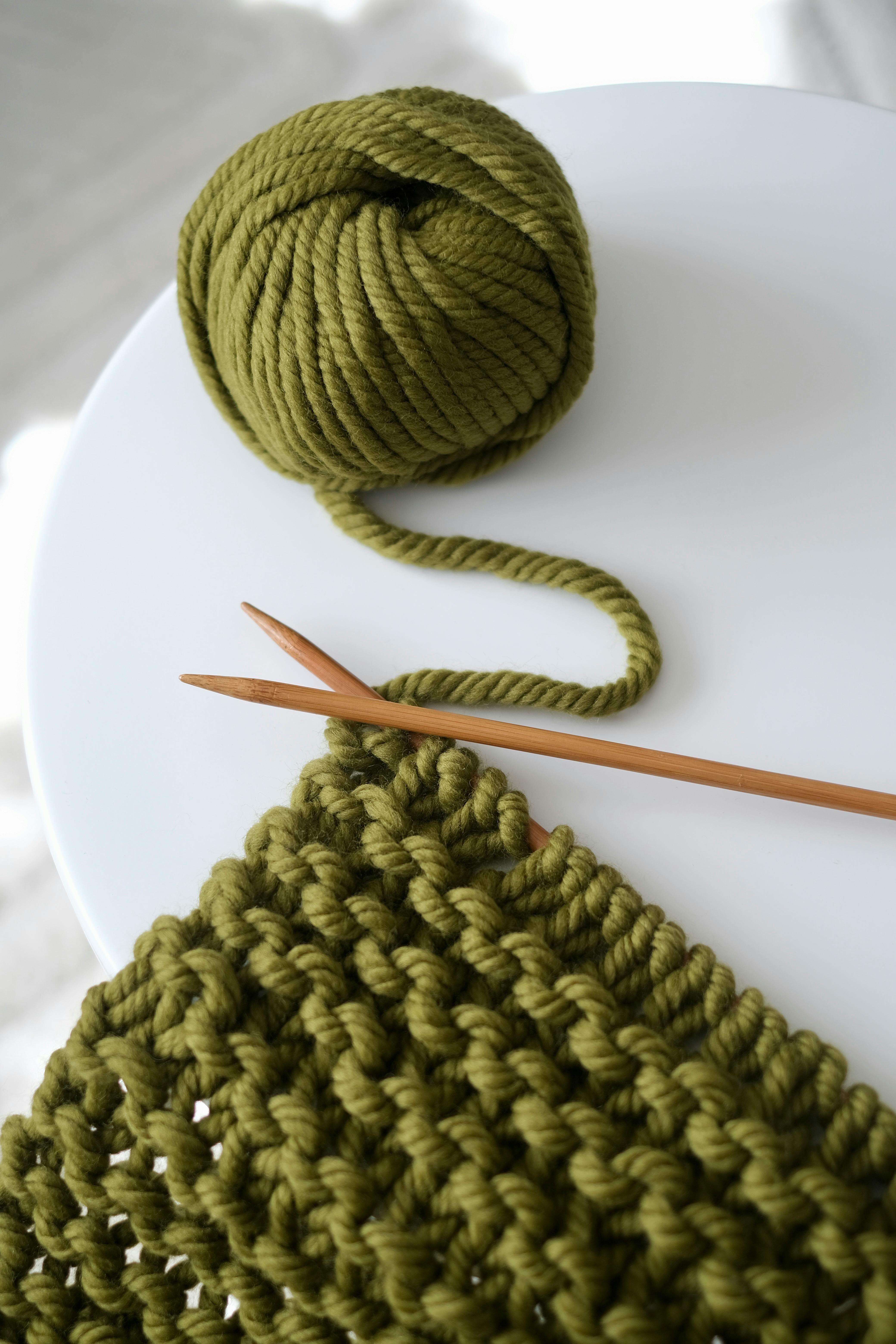 Green yarn and knitting needles on a table, showcasing crafting creativity.