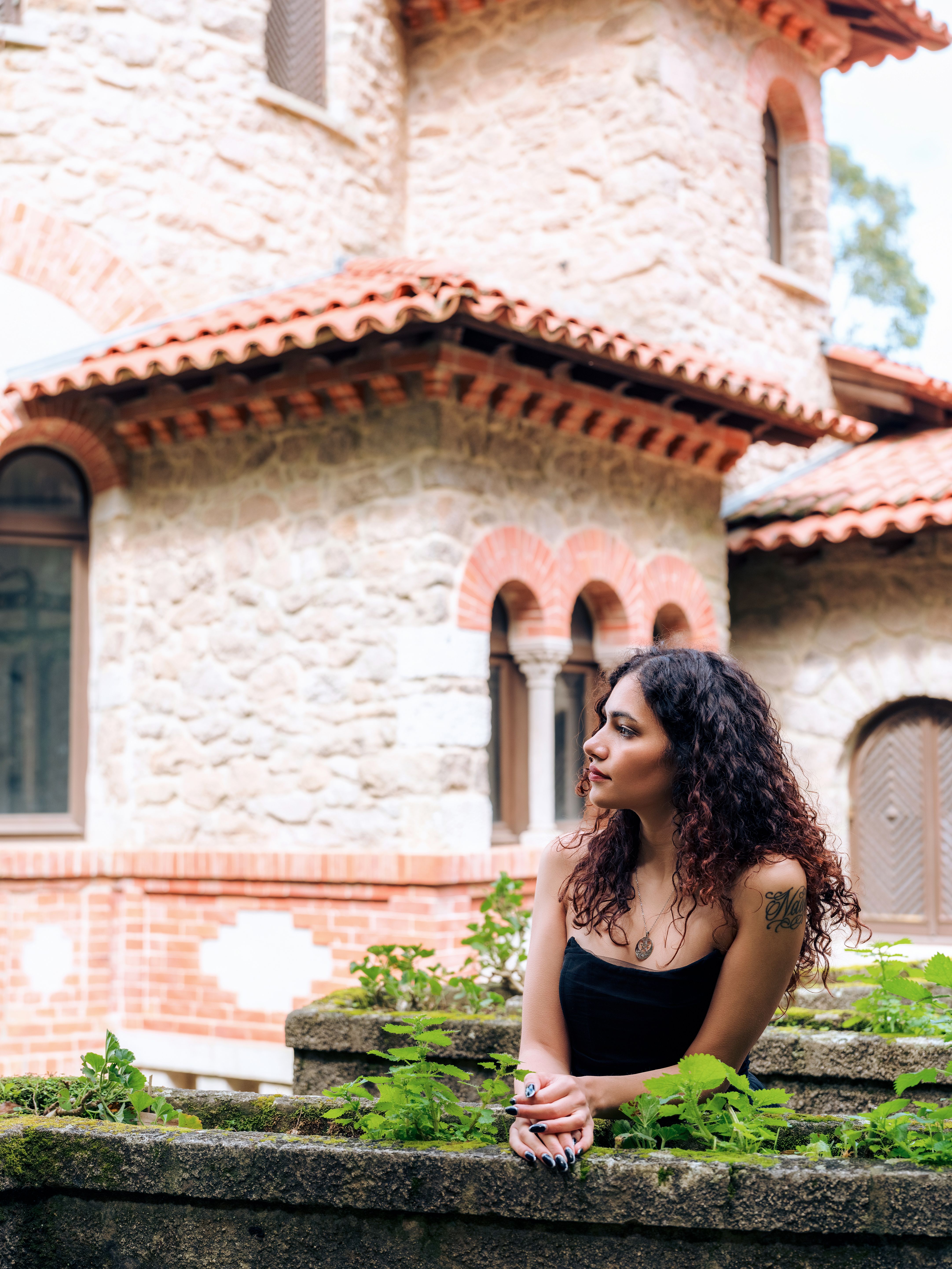 A serene portrait of a young woman in front of Villa Sassetti's historic architecture in Sintra, Portugal.