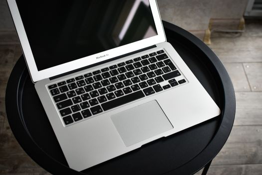 A stylish laptop sits elegantly on a black round table in an indoor setting, ideal for tech and workspace themes.