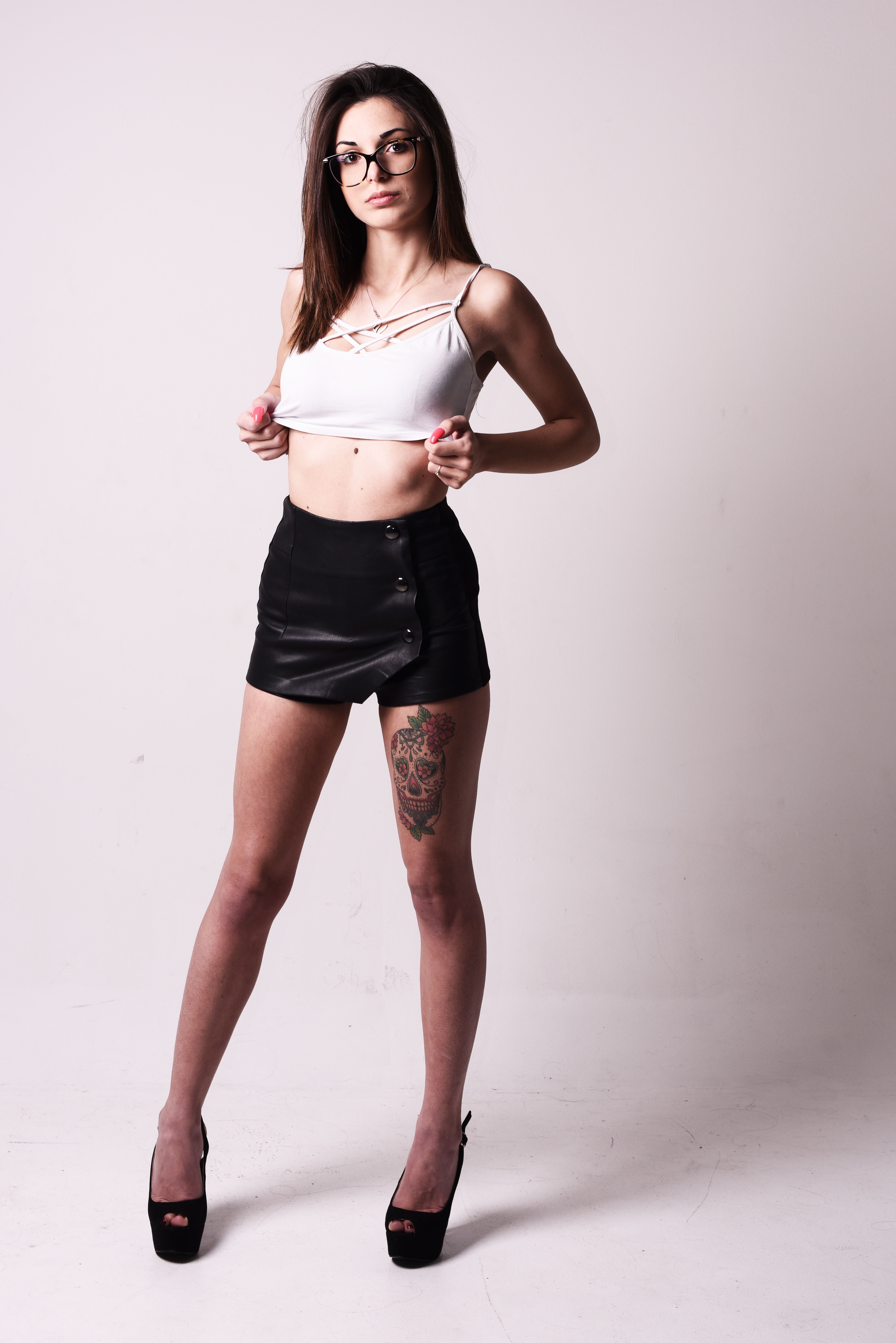Stylish young woman with tattoos modeling in a studio setting.
