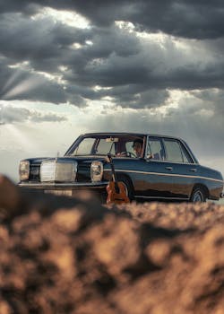 Classic vintage car with guitar in Agafay Desert, Morocco under dramatic skies.