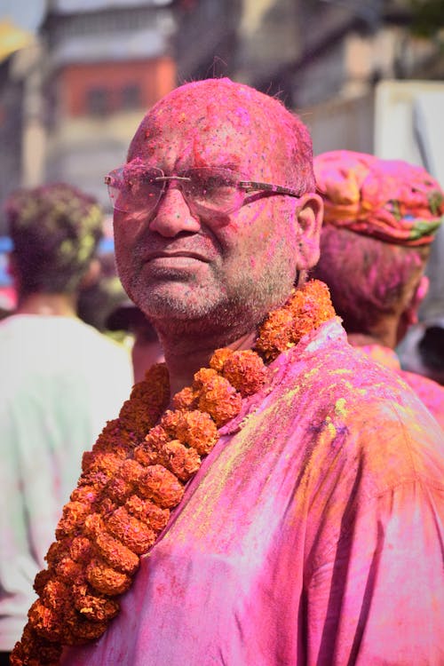 A man covered in colored powder and flowers