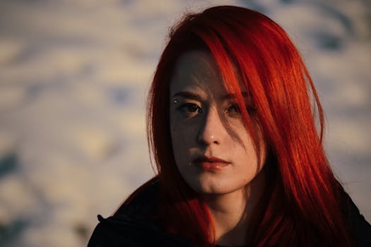 Close-up of a redhead woman outdoors with warm sunlight casting shadows on her face.