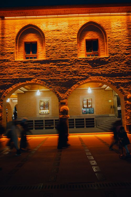 Free People walking at night under illuminated arches in an urban setting, creating vibrant atmosphere. Stock Photo