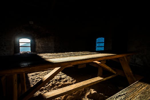 在一个黑暗的石头房间里，阳光透过窗户照射在木制野餐桌上