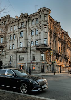 Luxury black car parked on urban street in Türkiye, near historic building.