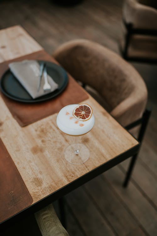 A glass of wine sits on a wooden table