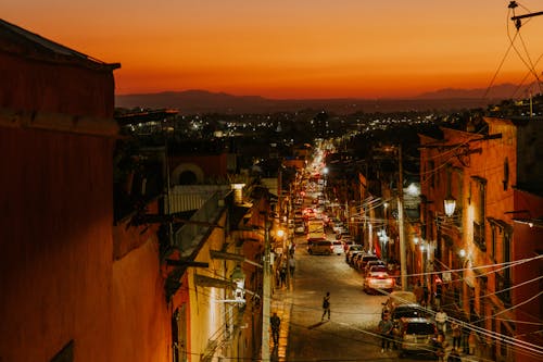 A city street at sunset with cars and people