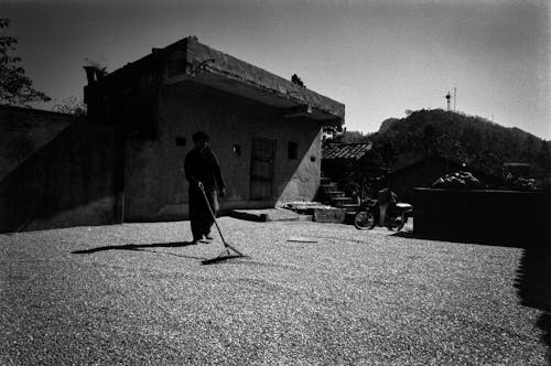 A man is walking on the street with a broom