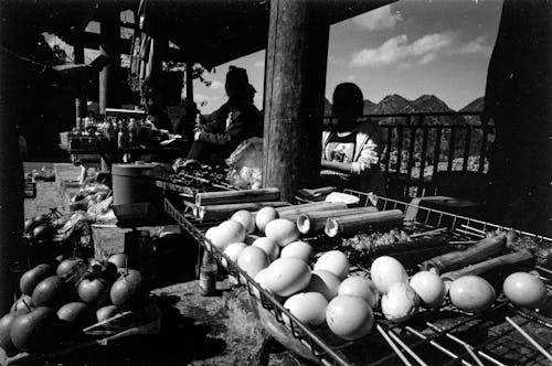 A black and white photo of a market with eggs and vegetables