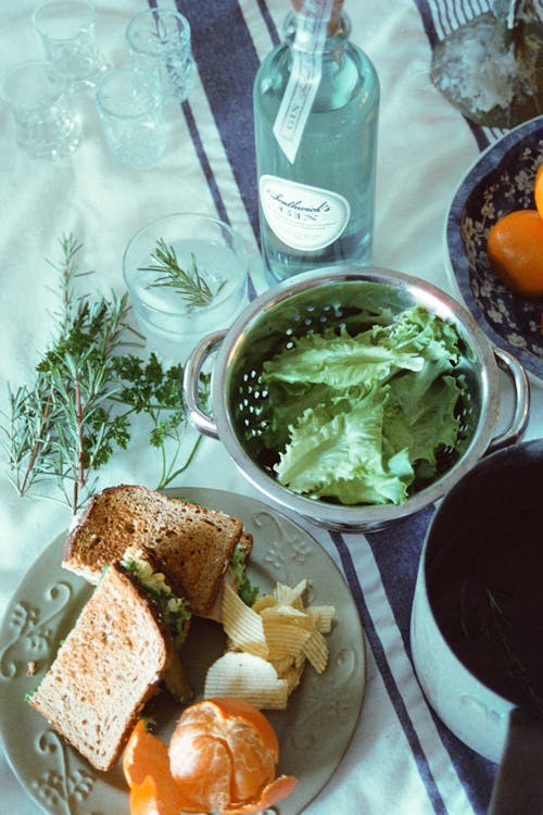 A table with a sandwich, orange slices, and a bottle of wine