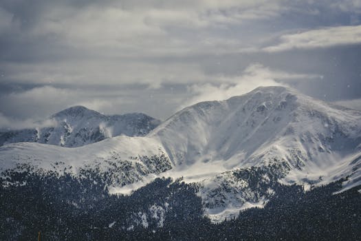 Explore the serene beauty of snow-covered mountains under a cloudy winter sky.