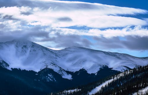 бесплатная Гора, покрытая снегом под белым и голубым небом Стоковое фото