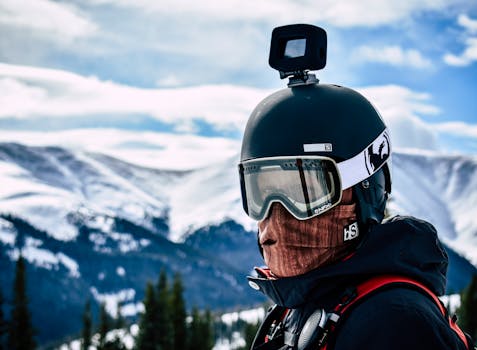雪山风景中，一名滑雪者头戴摄像机，特写镜头展现了冬季运动的冒险感