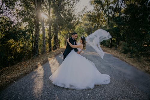 A bride and groom are standing in the middle of a road